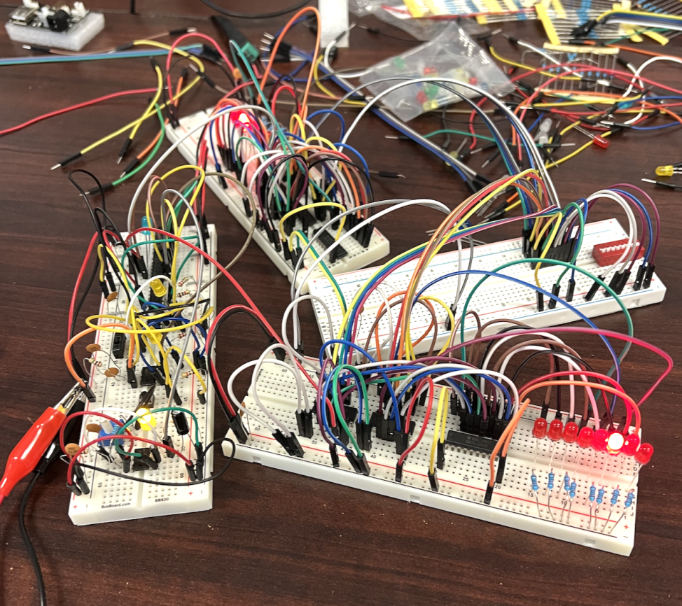 A photo of four breadboards covered in wire. They are loosely connected with wire.