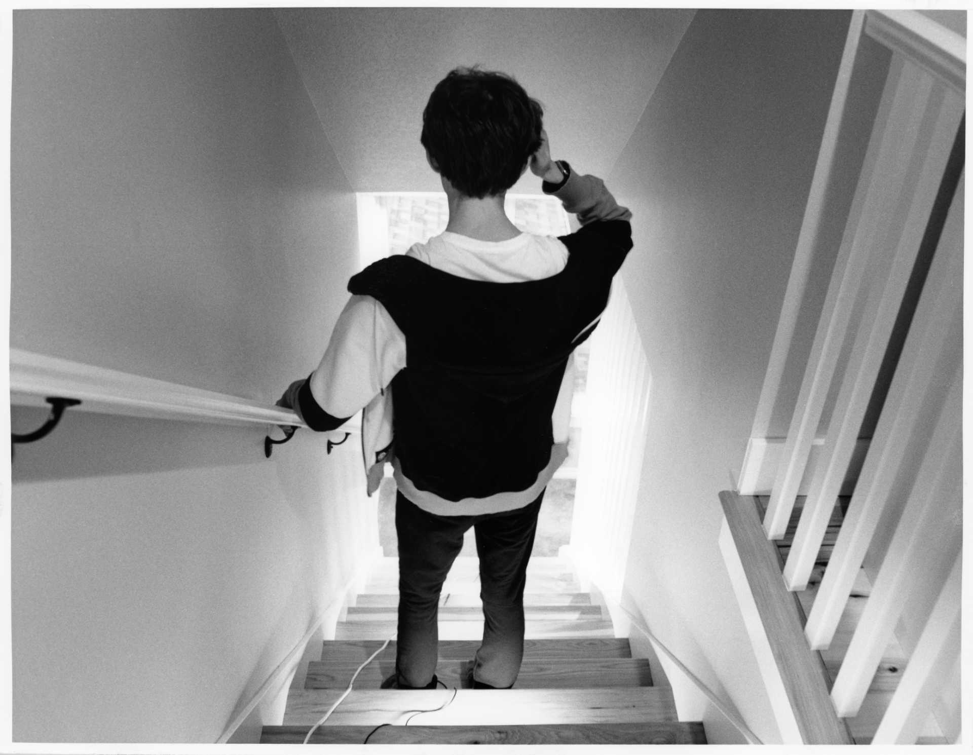 Black and white photo of me walking down the stairs, my right hand is in my hair.