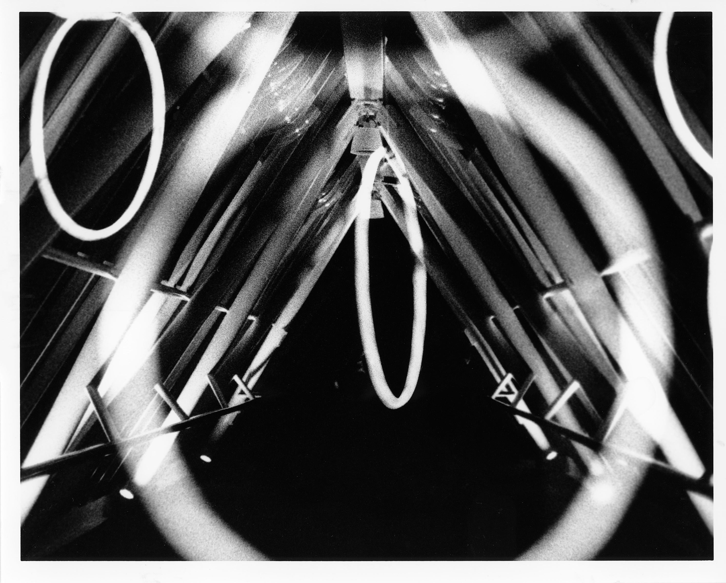 Black and white photo of light up circles in front of a triangle shaped hallway.