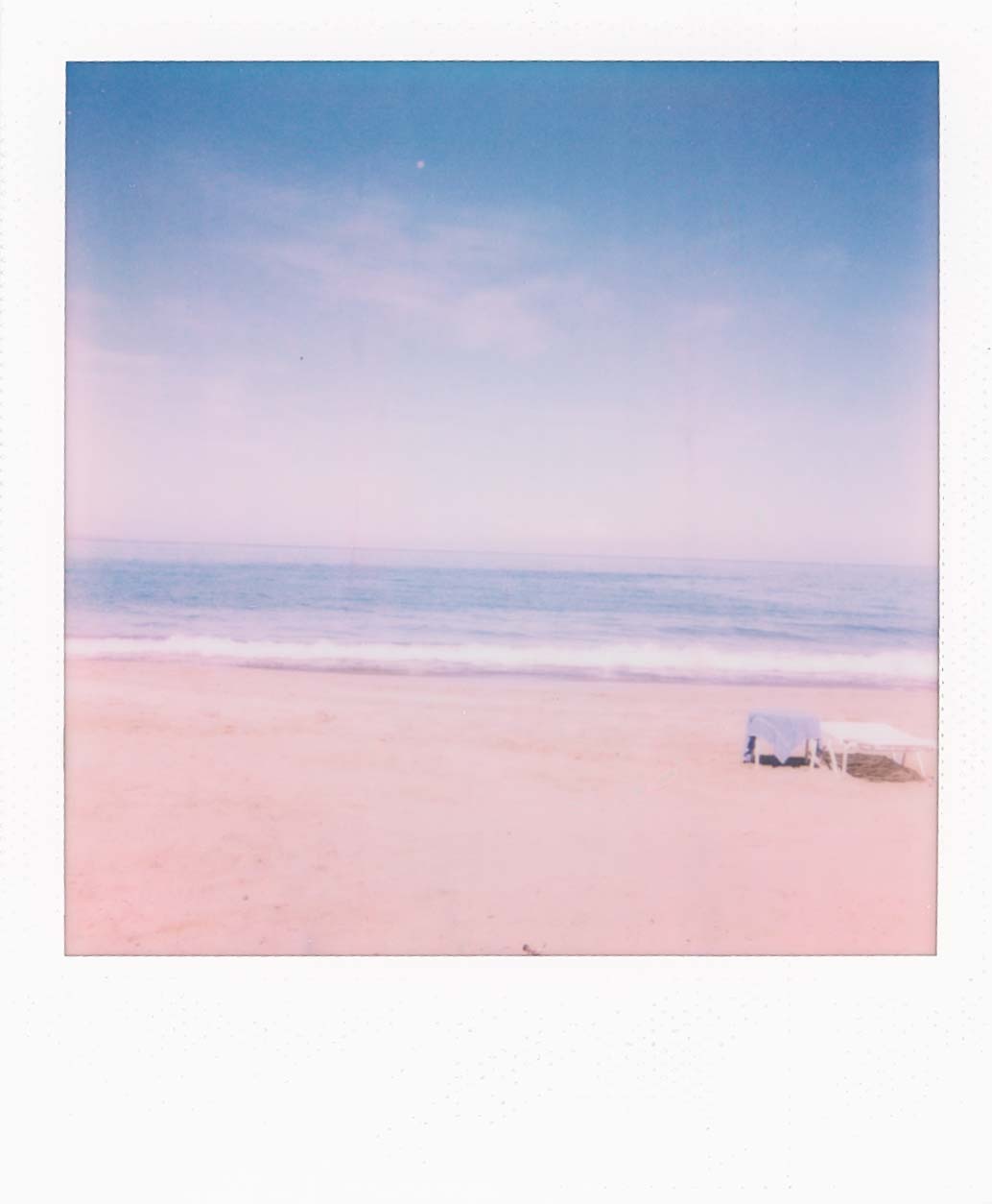 Landscape of a beach during the day. A chair and table are off to the right.