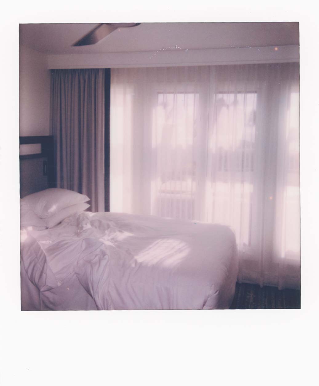 Photo of a white messy bed with light coming from the curtains.